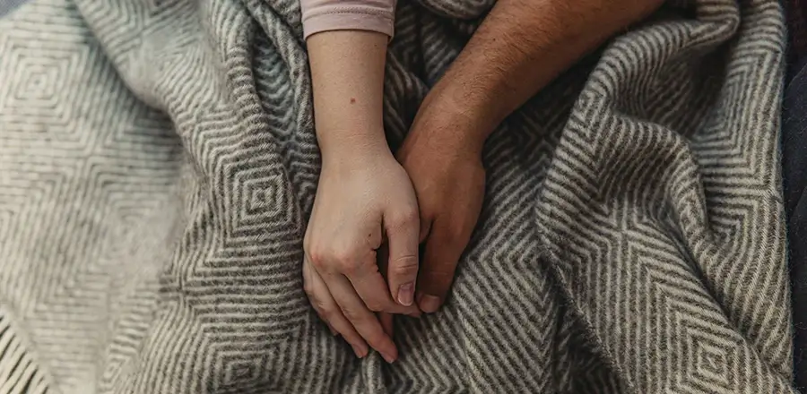 Man and woman holding hands on top of blanket